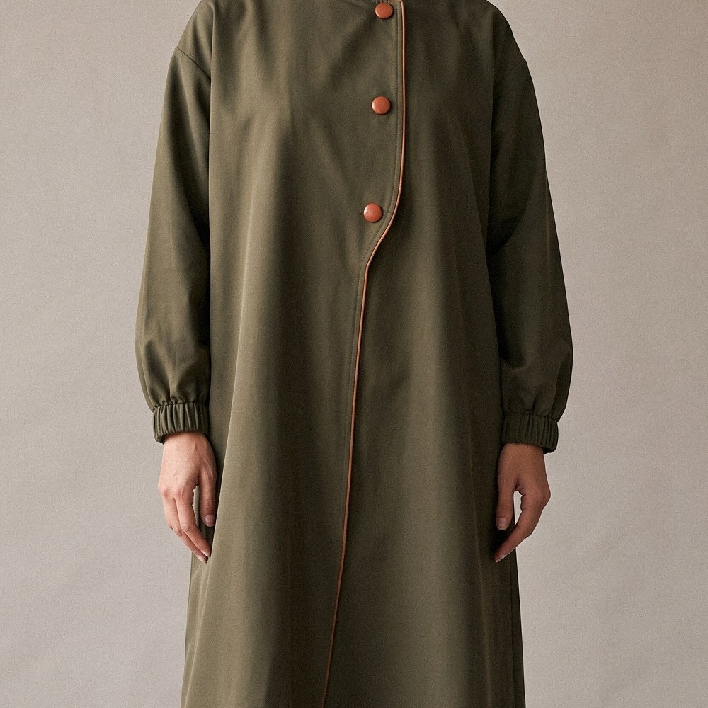 Close-up of the camel piping and camel buttons along the curved front opening of the Green Trench Coat Abaya.