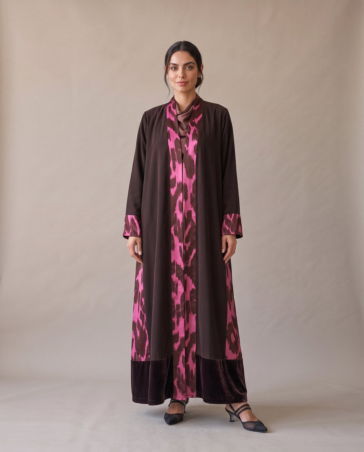 The Brown Velvet Abaya with Pink Print from the front: a pink print panel down the opening and at the cuffs, over a velvet hem.
