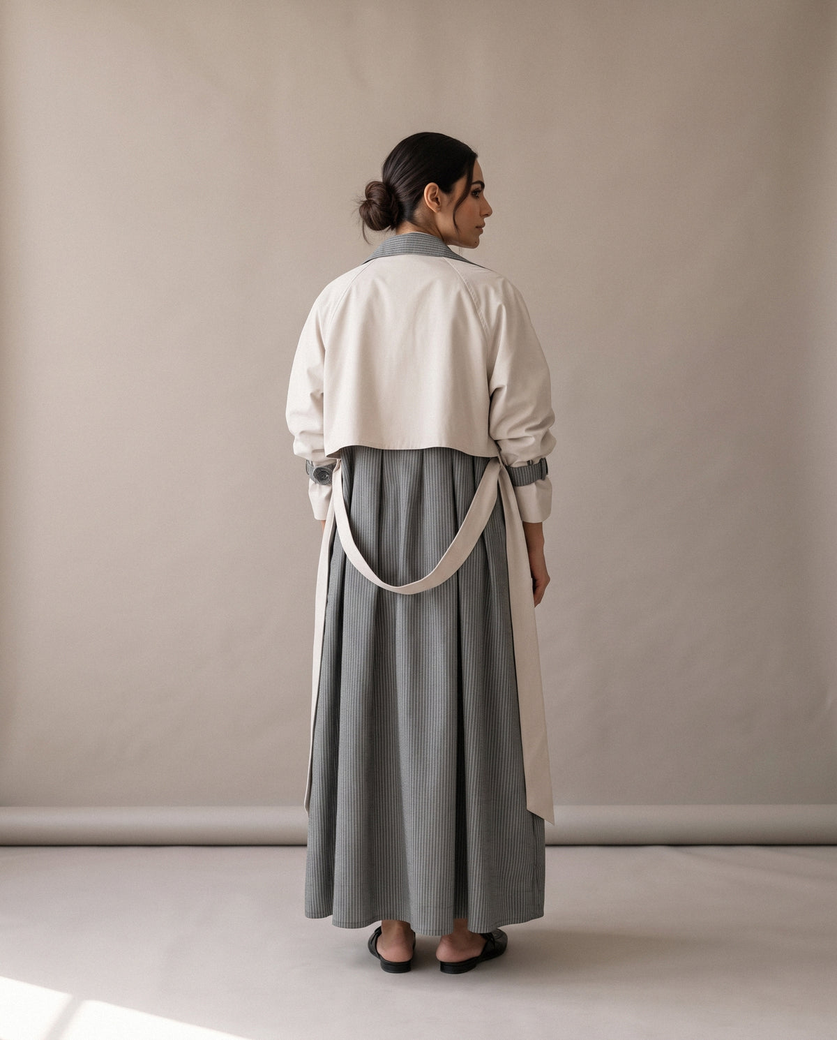 The Grey & Beige Trench Coat Abaya from the back: a beige yoke and belt over grey striped pleats.