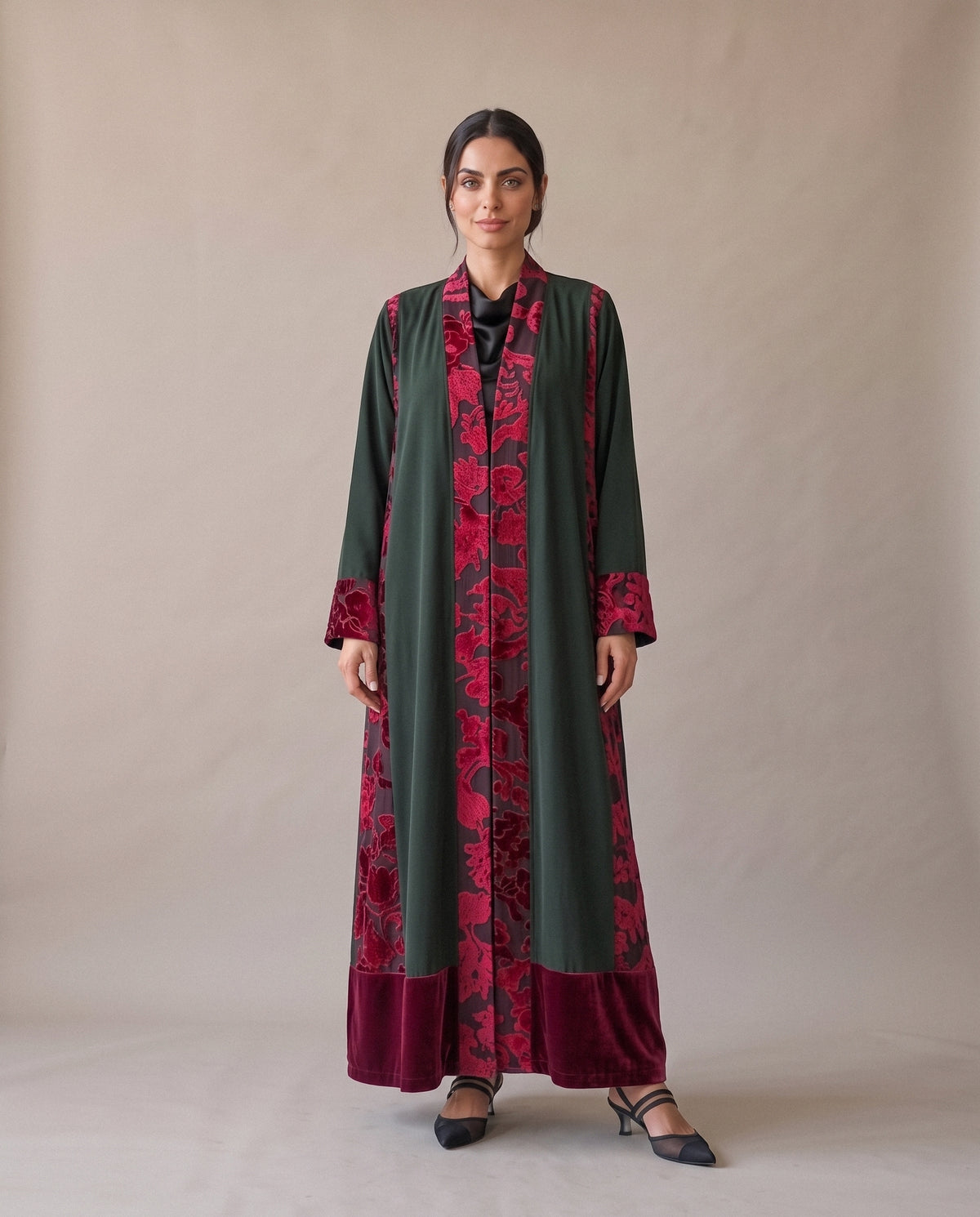 The Green Velvet Abaya from the front: crimson floral velvet along the opening and the cuffs, over a crimson velvet hem.